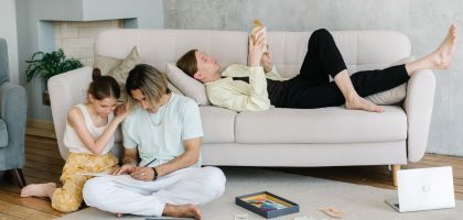 Father and daughter bonding in cozy living room with books and games, creating joyful family moments.